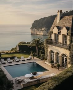 an aerial view of a house with a swimming pool in the foreground and ocean in the background