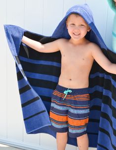 a young boy standing under a blue and black towel with his hands on his hips