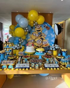 a table topped with lots of desserts and balloons in the shape of minion's