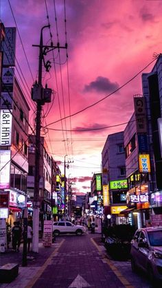 a city street filled with lots of traffic under a colorful sky