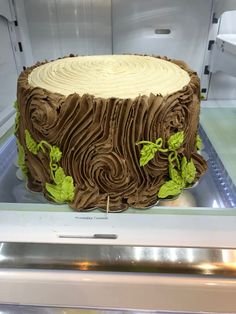 there is a cake that looks like a tree stump with leaves on it and frosting