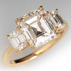 three stone engagement ring with an emerald and baguette cut diamond in yellow gold