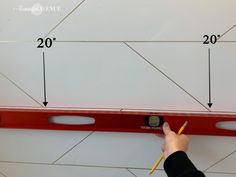 a person holding a pencil and measuring the width of a wall