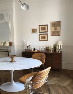 a dining room table with chairs and pictures on the wall behind it in an apartment