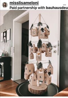 a christmas tree made out of cardboard with houses and ornaments hanging from it's sides