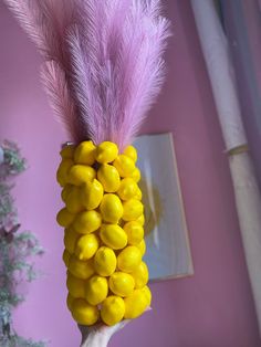 a hand holding a yellow and pink candy cornucre with purple feathers on it