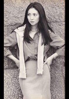 a woman standing in front of a wall with her hands on her hips