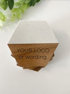 a wooden block with the words your logo or wording on it next to a plant