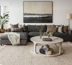 a living room filled with furniture and a large painting on the wall above it's coffee table