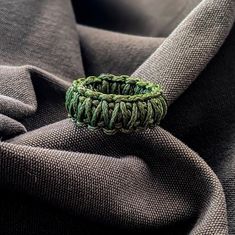 a green ring sitting on top of a piece of cloth covered in grey fabric material