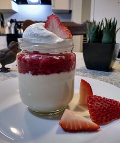 a strawberry cheesecake in a jar with whipped cream and strawberries