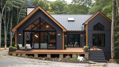 a black house with lots of windows in the woods