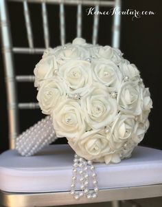 a bouquet of flowers sitting on top of a chair with pearls and pearls around it