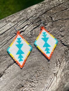 a pair of earrings made out of bead and plastic beads sitting on top of a piece of wood