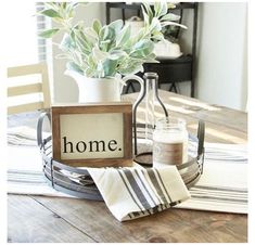 a wooden table topped with a vase filled with flowers next to a sign that says home