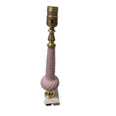 a pink glass and brass candle holder on a marble base with a gold plated top