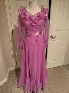 This brand new never worn 1970's Pink Prairie ruffled neckline Sheer puff sleeves Maxi dress Southern Belle dress comes to you in a size S. As you can see in the back of the dress has a ruffled lay down back with satin trim and a satin belt-There is a ruffle at the bottom-This dress has never been worn-the tags are crisp inside-Such a great retro Maxi dress-Pls compare the measurements I give you to those in your closet-They are as follows- - Vintage Pink Dress With Ruffles, 70s Prom Dress, Pink Cottagecore Vintage Dress With Ruffles, Pink Gunne Sax Dress, Southern Belle Dress, 70s Mode, 1970s Pink Long Sleeve Dress, 80s Prom Dress, 1970s Ruffled Vintage Day Dress