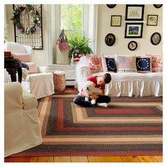 a young boy sitting on the floor in front of a living room rug holding a teddy bear