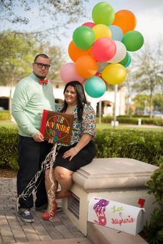 a man and woman standing next to each other with balloons