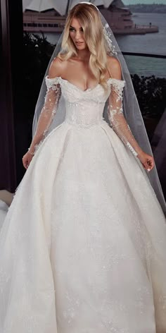 a woman in a white wedding dress standing next to a window