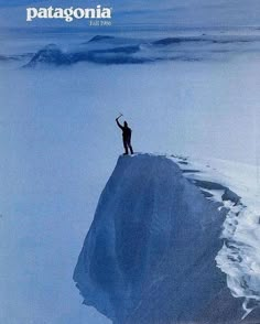 a man standing on top of a snow covered mountain with his arms in the air