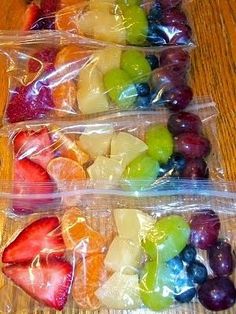 four plastic bags filled with fruit on top of a wooden table