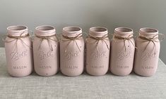 six pink mason jars tied with twine and labeled ball mason are lined up in a row