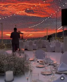 a man standing on top of a roof next to tables covered in white cloths