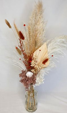 a vase filled with dried flowers and feathers