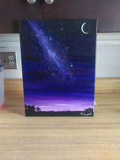 a painting on a wooden table with a purple sky and stars