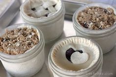 four desserts in small white containers on a metal tray