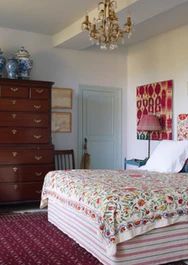 a bed sitting in a bedroom next to a dresser and chair on top of a rug