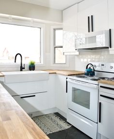 a kitchen with white appliances and wooden counter tops in front of a large open window