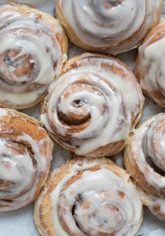 cinnamon rolls with icing sitting on top of each other