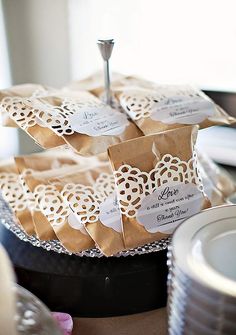 some brown paper bags with white tags on them sitting on a table next to plates and silverware