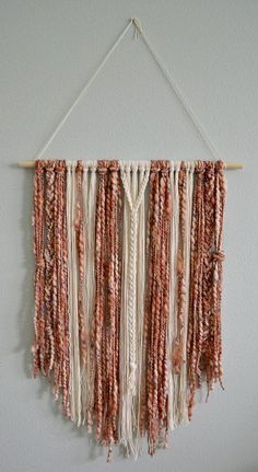 a wall hanging with beads and tassels attached to it's sides on a white wall