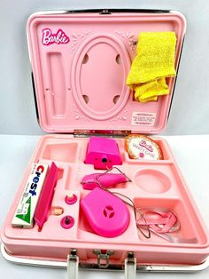 a pink suitcase filled with lots of items like scissors, hairdryer and yellow towel