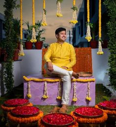 a man sitting on top of a purple bench next to baskets filled with fruit and flowers