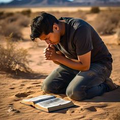 a man kneeling down in the sand with his hands folded over an open book and praying