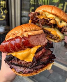 a person holding up a large hamburger with meat and cheese