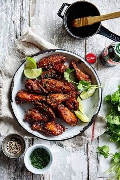 chicken wings on a plate with garnishes and seasoning next to it