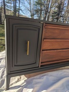 an old dresser has been painted black and brown with gold hardware on the door handle