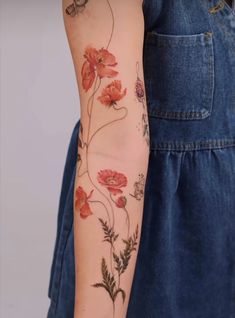 a woman's arm with red flowers and leaves on the left side of her arm