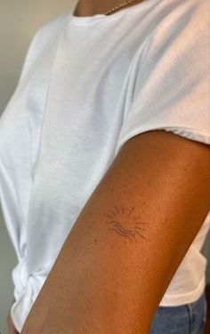 a woman's arm with a small sun tattoo on the left side of her arm