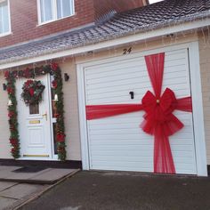 two garage doors decorated with christmas wreaths and red ribbon