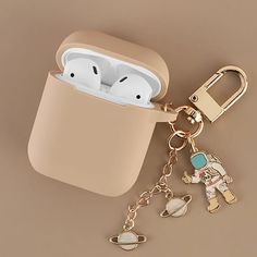 an apple airpods case sitting on top of a keychain with charms attached to it