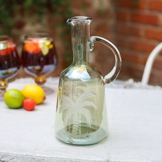 a glass bottle sitting on top of a table next to some lemons and limes