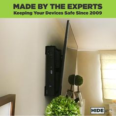 a tv mounted to the side of a wall next to a green potted plant