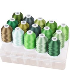 many spools of thread are in a plastic container on a white background,