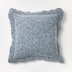 a blue and white pillow sitting on top of a white table next to a wall